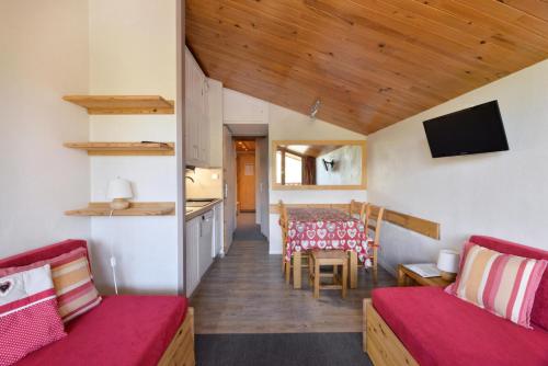 un salon avec deux canapés rouges et une cuisine dans l'établissement Résidence Andromede - 2 Pièces pour 5 Personnes 84, à Mâcot La Plagne