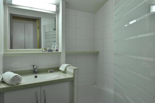 une salle de bain blanche avec un lavabo et un miroir dans l'établissement Résidence Andromede - 2 Pièces pour 5 Personnes 84, à Mâcot La Plagne