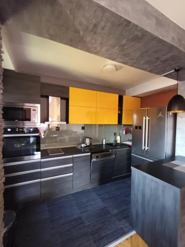 a kitchen with stainless steel appliances and yellow cabinets at Nena Apartment in Kumanovo