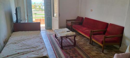 a living room with a red couch and a table at Marakia beach in Dawwār ‘Abd al Qādir Qāsim