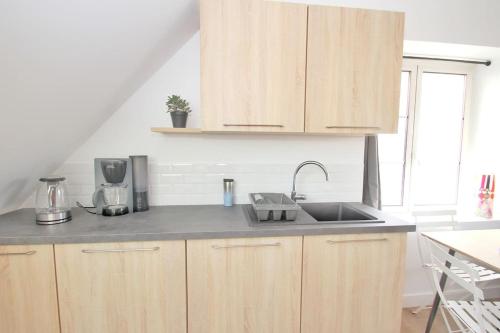 une cuisine avec des armoires en bois et un évier dans l'établissement Les appartements Isabelle 5 - Centre Ville, à Lorient