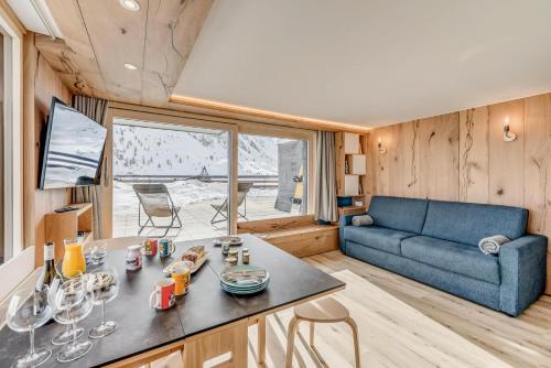 un salon avec un canapé bleu et une table dans l'établissement Résidence Palafour - Rénovation et confort moderne pour ce studio avec terrasse vue lac MAE-3731, à Tignes