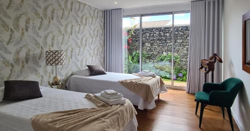 a bedroom with two beds and a chair and a window at Magnolia Residence - central to explore the island in Ribeira Grande