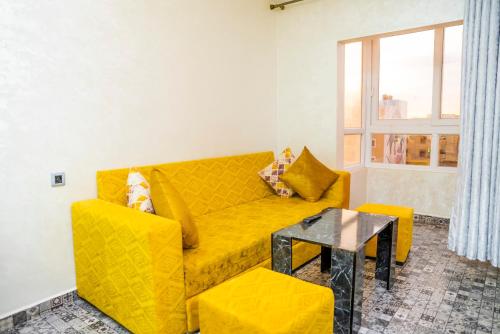 a living room with a yellow couch and a table at Lilia Quest in Dakhla