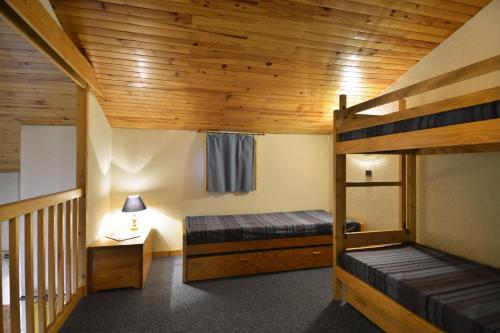 Cette chambre comprend deux lits superposés et une table avec une lampe. dans l'établissement Résidence Agate - 3 Pièces pour 7 Personnes 53, à Mâcot La Plagne
