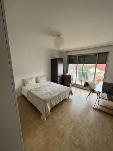 une chambre avec un lit et une grande fenêtre dans l'établissement Très grand appartement au Raincy, à Le Raincy