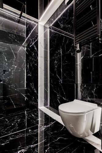 a bathroom with a white toilet in a black wall at Aqua Bluemica ADULTS ONLY in Międzyzdroje
