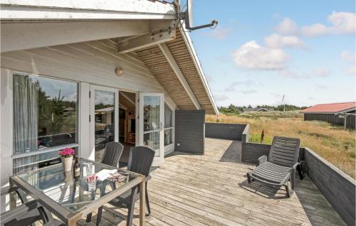 a patio with chairs and a glass table on a deck at Awesome Home In Hvide Sande With Sauna in Bjerregård