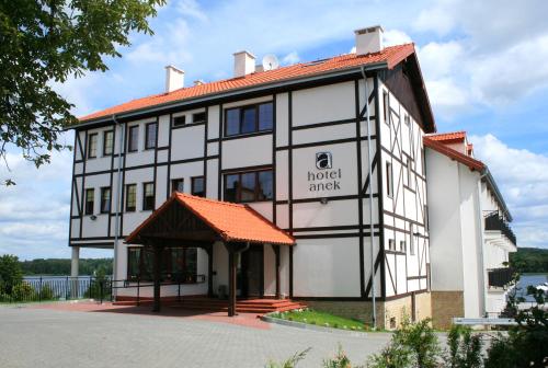 a large white building with an orange roof at Hotel Anek in Mrągowo