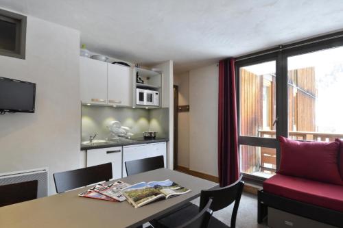 un salon avec une table et un canapé rouge dans l'établissement Résidence Carroley B - 2 Pièces pour 6 Personnes 12, à Mâcot La Plagne