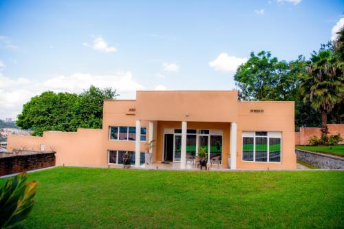 a building with a green lawn in front of it at Fleur Guest House in Kigali
