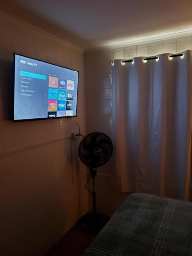 a bedroom with a flat screen tv and a fan at Pousada Monte Gerizim in Sao Paulo