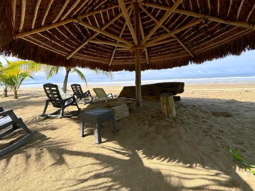 a beach with chairs and a large straw umbrella at Kudos Boutique Hotel in Cabrera