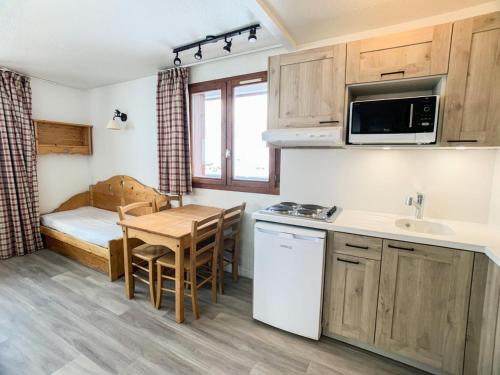 - une petite cuisine avec une table et un lit dans une chambre dans l'établissement Résidence Rond Point Des Pistes A - Appartement proche des pistes·Balcon MAE-6728, à Tignes