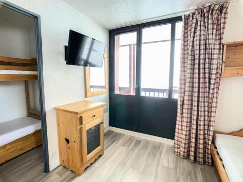 Cette chambre comprend un lit, une télévision et une fenêtre. dans l'établissement Résidence Rond Point Des Pistes A - Appartement proche des pistes·Balcon MAE-6728, à Tignes