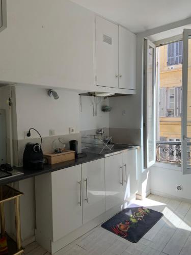 une cuisine avec des armoires blanches et une fenêtre dans l'établissement Quartier Trendy proche de Tous les sites, à Marseille