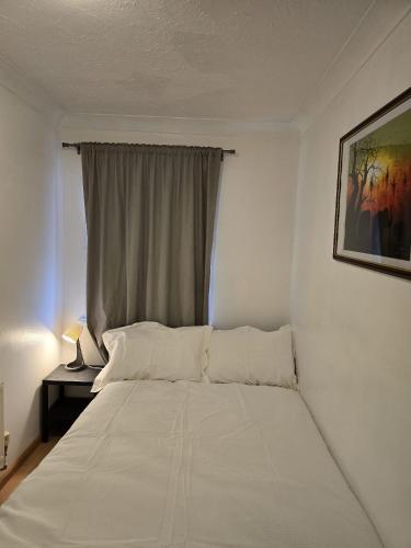 a white bed in a room with a window at MeadThames View in Thamesmead