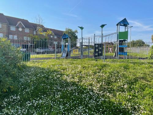 a playground with a slide in a field of flowers at MeadThames View in Thamesmead
