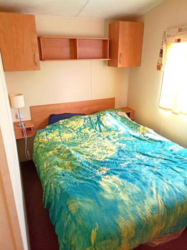 une chambre avec un lit avec une couette bleue dans l'établissement Mobil-home 4 à 6 personnes camping paradis 4 étoiles, à Clohars-Carnoët