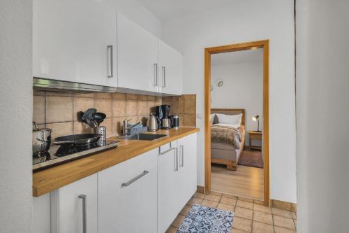 a kitchen with white cabinets and a bed in a room at HIRSCH Stadt Apartment 3 - Balkon mit Flussblick - Parkplatz in Bad Harzburg