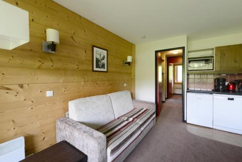 - un salon avec un canapé et un mur en bois dans l'établissement Résidence Quartz - 2 Pièces pour 4 Personnes 284, à Mâcot La Plagne