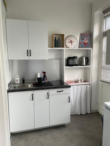 une cuisine avec des armoires blanches et un évier dans l'établissement Appartement studio avec terrasse et jardin privés, à Boulogne-sur-Mer
