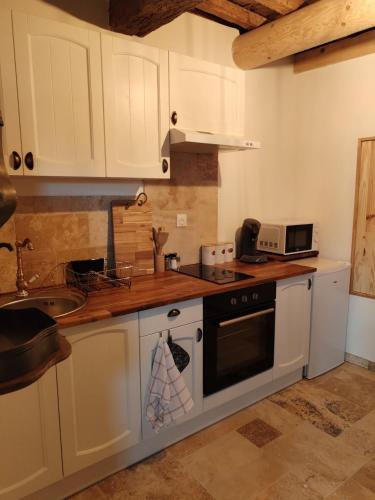 a kitchen with white cabinets and a stove top oven at La Tanière in Lagarde-Paréol