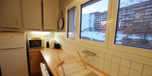une cuisine avec une fenêtre et un comptoir avec un four micro-ondes dans l'établissement Résidence Cimes - Très belle vue Lac et Grande Motte MAE-7774, à Tignes