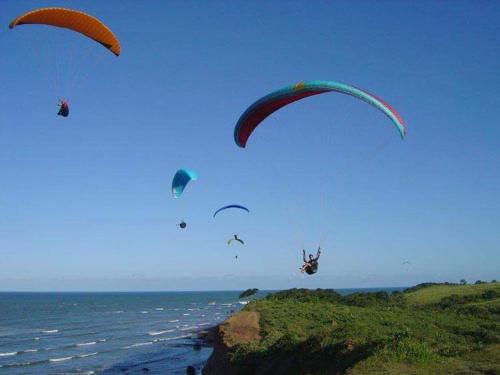 a group of people flying kites over the ocean at Pousada dos Veleiros in Nova Almeida