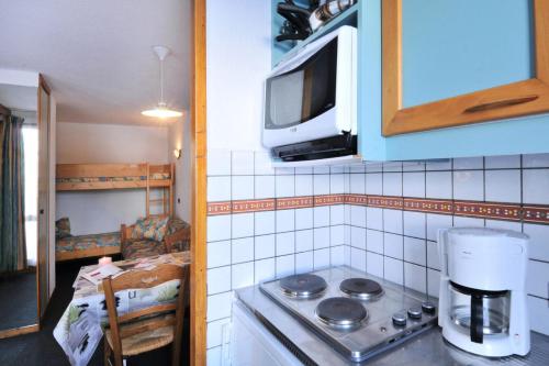 une cuisine avec une cuisinière et un micro-ondes dans l'établissement Résidence Agate - Studio pour 4 Personnes 244, à Mâcot La Plagne
