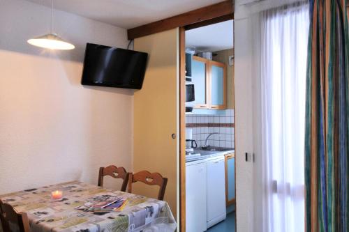 une cuisine avec une table et une télévision murale dans l'établissement Résidence Agate - Studio pour 4 Personnes 244, à Mâcot La Plagne