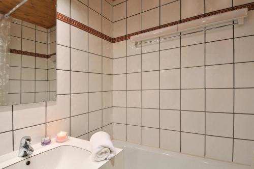 La salle de bains est pourvue de carrelage blanc, d'un lavabo et d'une baignoire. dans l'établissement Résidence Agate - Studio pour 4 Personnes 244, à Mâcot La Plagne