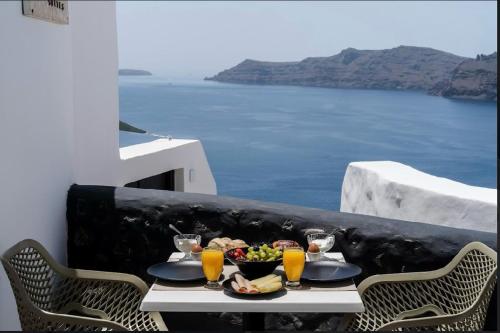 a table with food and drinks on a balcony with the ocean at Enalion Suites in Oia