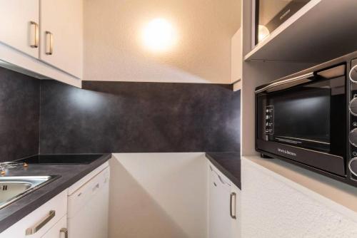 une cuisine avec un évier et un micro-ondes dans l'établissement Résidence La Traverse - Studio entièrement rénové MAE-8924, à La Plagne Tarentaise