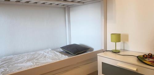 - une chambre blanche avec un lit et une lampe sur une table dans l'établissement Résidence Choucas - 3 Pièces pour 7 Personnes 244, à La Plagne Tarentaise