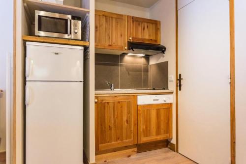 une cuisine avec des armoires en bois et un réfrigérateur blanc dans l'établissement Le Chalet De Montchavin - Bel appartement duplex proche du centre MAE-4254, à La Plagne Tarentaise