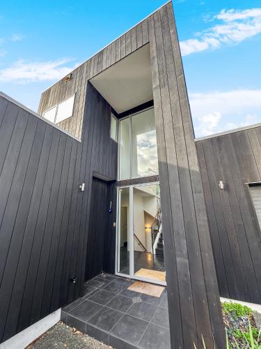 a modern house with a black exterior at Murrays Gem l Modern 4bed Stunner l Sea View & Spa! in Auckland