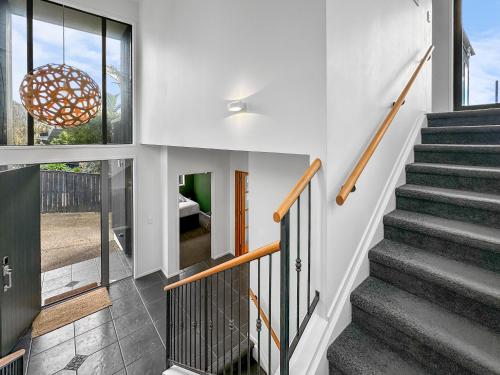 a staircase in a house with white walls at Murrays Gem l Modern 4bed Stunner l Sea View & Spa! in Auckland