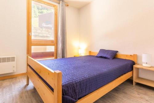 une chambre avec un lit avec une couette bleue et une fenêtre dans l'établissement Résidence Le Tetras Lyre - Au pied du télécabine bel appartement MAE-4494, à La Plagne Tarentaise
