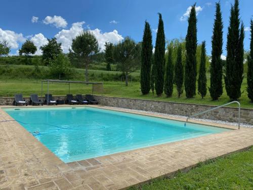 a swimming pool with chairs and trees in the background at Casa Montecastelli Sopra/Terra in Monte Castelli