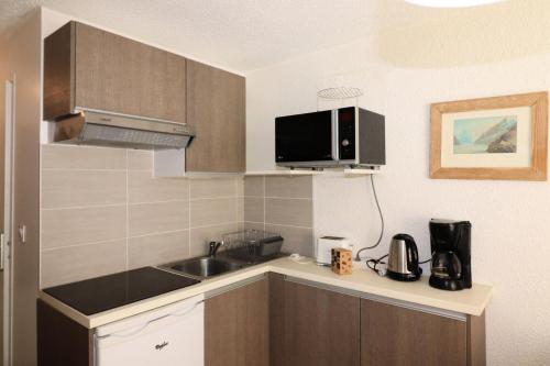 une petite cuisine avec un évier et un micro-ondes dans l'établissement Résidence Olympiques - Studio à Tignes 1800 MAE-7484, à Tignes