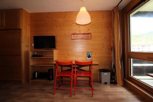 - une salle à manger avec deux chaises rouges et une table dans l'établissement Résidence Tour Du Lac - Studio rénové·Proche des pistes ·Balcon MAE-7454, à Tignes
