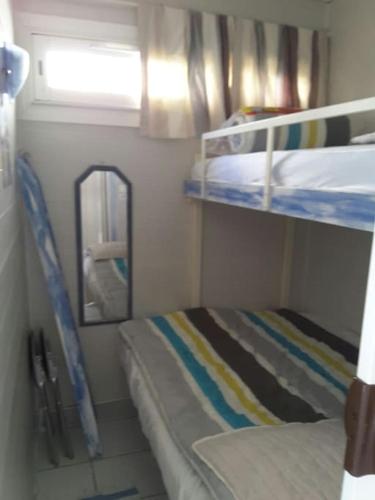 une petite chambre avec deux lits superposés et une fenêtre dans l'établissement Appartement RDC avec Terrasse dans residence avec piscine et face à la plage, à Leucate