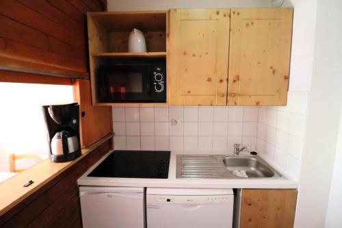 une cuisine avec un évier et un micro-ondes dans l'établissement Résidence Rond Point Des Pistes C - Studio·Proche des pistes·Balcon MAE-7514, à Tignes