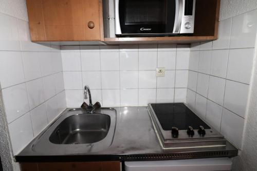 une cuisine avec un évier et un micro-ondes dans l'établissement Résidence Rond Point Des Pistes B - Studio·Proche des pistes·Balcon MAE-7734, à Tignes