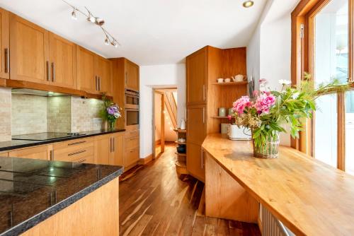 a kitchen with wooden cabinets and a counter with flowers on it at The Retreat, South Milton, Close to Salcombe in Kingsbridge