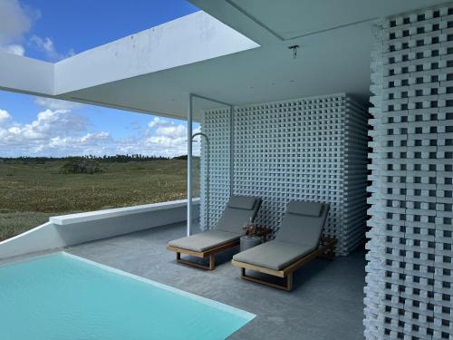 two chairs sitting on a balcony next to a swimming pool at Pousada Mestizo in São Miguel do Gostoso