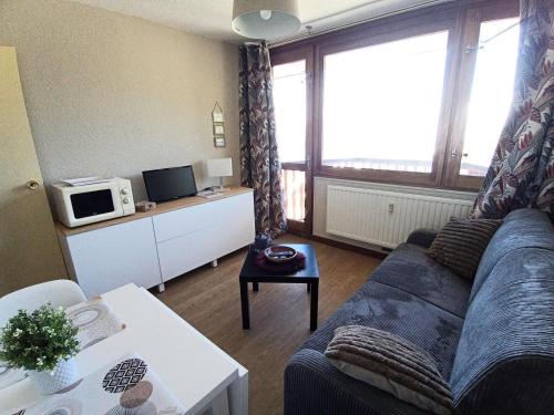 un salon avec un canapé bleu et un four micro-ondes dans l'établissement Résidence Le France - Studio confort 2 personnes Plagne Centre MAE-2834, à Aime La Plagne