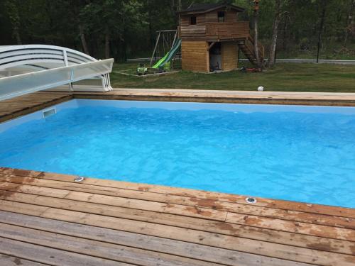 une grande piscine bleue avec une terrasse en bois dans l'établissement Villa Lou Bercail HOURTIN - 10 personnes, à Hourtin