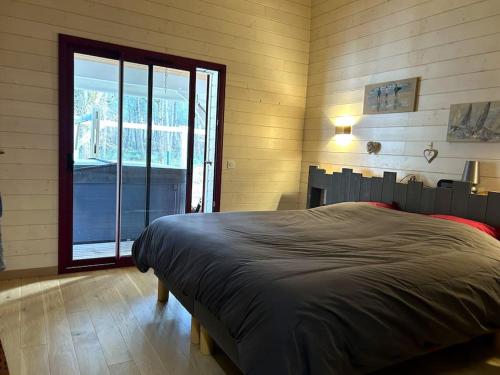 a bedroom with a large bed and a large window at Villa Lou Bercail HOURTIN - 10 personnes in Hourtin